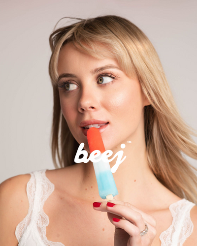 Woman holding a colorful popsicle with 'beej' branding against a plain background